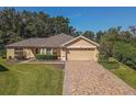 Single-story house with a tan exterior, brick driveway and landscaped yard at 13166 Se 86Th Cir, Summerfield, FL 34491