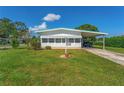 Mobile home with carport and a well-kept lawn at 903 Aloha Way, Lady Lake, FL 32159