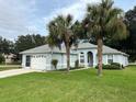 One-story home with light blue exterior, grey roof, and palm trees in the front yard at 11051 Sw 73Rd Ct, Ocala, FL 34476