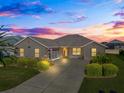 Attractive one-story home with a welcoming front porch at dusk at 16895 Se 110Th Court Rd, Summerfield, FL 34491