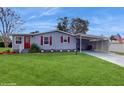 Gray single-wide manufactured home with red shutters, carport, and landscaped lawn at 820 Hibiscus Dr, Lady Lake, FL 32159