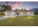 House exterior at dusk showcasing a teal front door and landscaping at 175 Fisher Way Trl, Ocklawaha, FL 32179