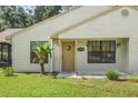 Front view of a house featuring a brown door, landscaping, and a beige exterior at 21174 Sw Peach Blossom St, Dunnellon, FL 34431