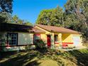 Yellow house with red trim, and a red door, and a white garage door at 39 Oak Pass Loop, Ocala, FL 34472