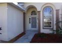 Front entrance with arched entryway, security door, and landscaping at 6688 Sw 113Th Pl, Ocala, FL 34476