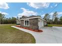 Side view of a single-story home with stone and a garage at 8540 Sw 136Th Ter, Dunnellon, FL 34432