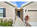 Front entry with a walkway leading to the front door of a tan house at 187 Hickory Course Trce, Ocala, FL 34472
