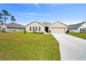 Tan house with a gray roof, two-car garage, and a landscaped lawn at 187 Hickory Course Trce, Ocala, FL 34472