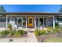 Inviting front porch with yellow door, bay window, and lush landscaping at 15330 Sw 59Th Ct, Ocala, FL 34473