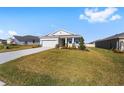 Landscaped yard with a one-story house, driveway, and other homes visible in the background at 6071 Sw 93Rd Loop, Ocala, FL 34476
