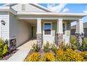Covered front porch with stone columns, light-colored door, and lush landscaping at 6071 Sw 93Rd Loop, Ocala, FL 34476