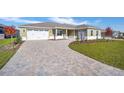 Landscaped front yard with paver driveway leading to a two-car garage at 9757 Sw 79Th Lane Rd, Ocala, FL 34481