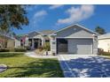 Single-story home featuring a gray exterior, two-car garage and lush landscaping at 15750 Sw 11Th Court Rd, Ocala, FL 34473