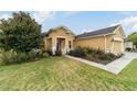 Tan house with a two-car garage and lush landscaping at 9948 Sw 69Th Ln, Ocala, FL 34481