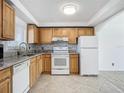 Bright kitchen with wood cabinets, granite counters, and white appliances at 100 Silver Beach Ave # 304, Daytona Beach, FL 32118