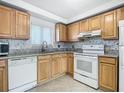 Bright kitchen with wood cabinets, granite counters, and white appliances at 100 Silver Beach Ave # 304, Daytona Beach, FL 32118