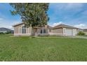Tan house with a large tree in front, double garage, and well-manicured lawn at 5065 Nw 21St Loop, Ocala, FL 34482
