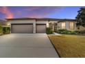 House exterior at dusk, three-car garage, and well-lit landscaping at 9733 Sw 74Th Pl, Ocala, FL 34481