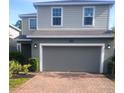 Two-story house with gray siding, brick driveway, and a two-car garage at 1609 Chelsea Manor Cir, Deland, FL 32724