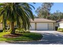 Tan house with a two-car garage and palm trees at 17066 Se 93Rd Yondel Cir, The Villages, FL 32162