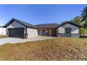 Single-story house with gray siding, black garage door, and a covered walkway at 13 Cedar Tree Run, Ocala, FL 34472