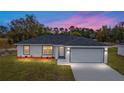 New construction home at sunset with a two-car garage and driveway at 10178 Sw 137 Ave, Dunnellon, FL 34432