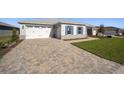 Home's exterior boasts a paver driveway and landscaped lawn at 9781 Sw 79Th Lane Rd, Ocala, FL 34481