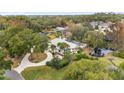 Aerial view of a home nestled among trees, featuring a circular driveway and a pond at 2023 Se Laurel Run Dr, Ocala, FL 34471