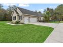 View of the home's side and three-car garage with a well-maintained lawn at 14225 Nw 145Th St, Williston, FL 32696