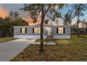 Gray manufactured home with a concrete driveway and landscaped lawn at dusk at 18478 Se 58Th Pl, Ocklawaha, FL 32179