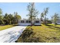 Gray manufactured home with a concrete driveway and grassy yard at 18478 Se 58Th Pl, Ocklawaha, FL 32179