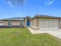 Tan house with blue door, screened garage, and grassy front yard at 5309 Sw 89Th Pl, Ocala, FL 34476