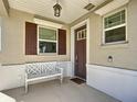 Front porch features a white bench and brown door at 7883 Sw 89Th Cir, Ocala, FL 34481