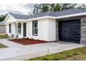 New home with white exterior, black garage door, and stone accents at 16919 Sw 27Th Ave, Ocala, FL 34473