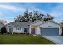 White house with blue garage door, landscaping, and a spacious lawn at 4707 River Ridge Dr, Leesburg, FL 34748