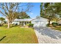 White house with gray roof, landscaped yard, and brick paver driveway at 10195 Se 178Th Pl, Summerfield, FL 34491