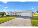 House with a white garage door and a brick paved driveway at 9862 Se 179Th Pl, Summerfield, FL 34491
