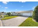 Front view of a house featuring a paved driveway and a neatly landscaped lawn at 9862 Se 179Th Pl, Summerfield, FL 34491