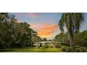 Ranch-style home with a metal roof, nestled on a lush, tree-lined lot at sunset at 6168 Arborea Dr, Lake Wales, FL 33898