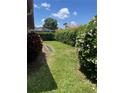 Small, grassy backyard with hedges and a paved pathway at 680 Augusta Rd, Winter Haven, FL 33884
