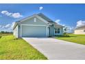 Newly built home with a light green exterior, two-car garage, and well-manicured lawn at 4073 Tullamore Ln, Auburndale, FL 33823