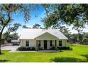 White farmhouse with metal roof, front porch, and lush landscaping at 12510 Lake Hatchineha Rd, Haines City, FL 33844
