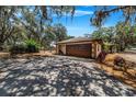 Attached garage with a brown door, surrounded by trees at 8881 Cypresswood Dr, Lake Wales, FL 33898