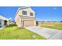 Two story house with tan siding, a two car garage, and landscaping at 1472 Leamington Ln, Winter Haven, FL 33884