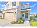 Two story house with tan siding, a two car garage, and landscaping at 1472 Leamington Ln, Winter Haven, FL 33884
