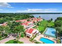 Aerial view of a waterfront community with a pool, tennis court, and many houses at 4 Casarena Ct, Winter Haven, FL 33881