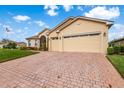Tan house with a brick driveway and attached garage at 4496 Strathmore Dr, Lake Wales, FL 33859