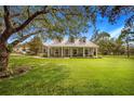 Gray farmhouse with wraparound porch, landscaping, and large yard at 8044 Lake Hatchineha Rd, Haines City, FL 33844