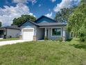 New house with gray exterior, white garage door, and nicely manicured lawn at 213 Cordova Rd, Auburndale, FL 33823