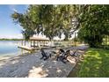 Lakefront firepit area with Adirondack chairs under oak tree at 121 E Lake Summit Dr, Winter Haven, FL 33884